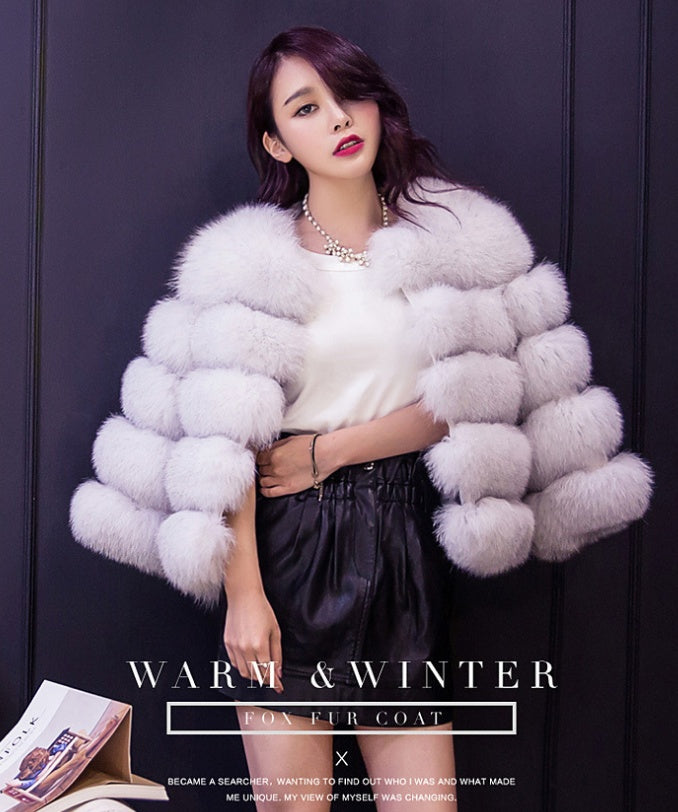Women’s white fur coat with wide collar and chunky horizontal puff layers.